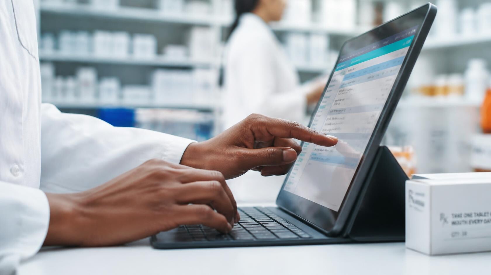 Professionele foto van handen van een apotheker die een melding maken op een tablet of computer, close up van handen op toetsenbord of touchscreen, moderne apotheek setting, natuurlijk licht, zakelijke sfeer